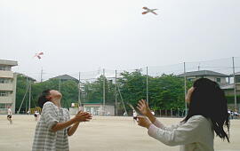子供たちが完成した十字プロペラを校庭で飛ばしてみる